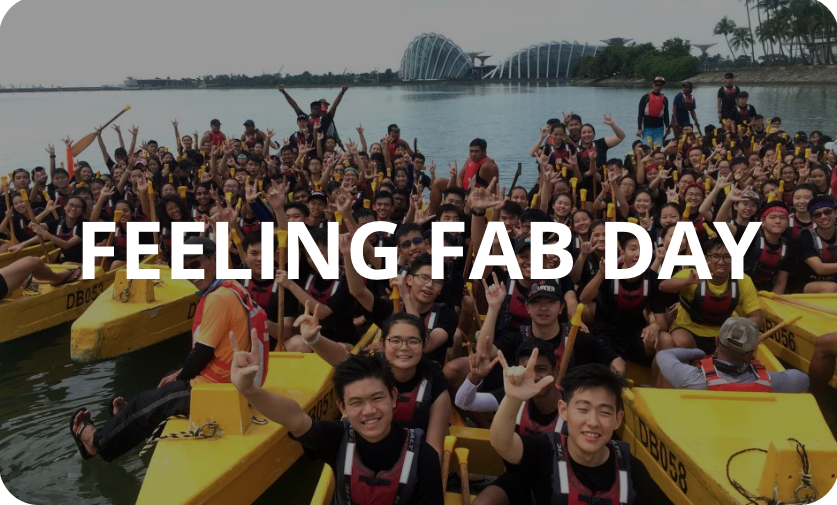 Large group of smiling people in life vests on yellow dragon boats on water, with text Feeling Fab Day.